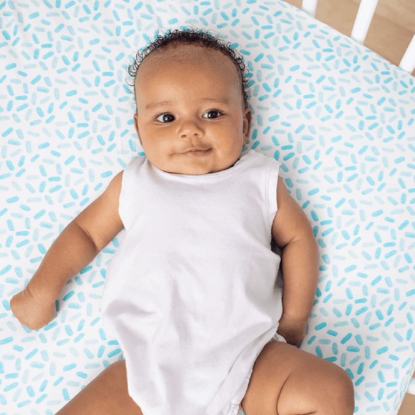 Baby laying on the Crib Sheets by Lovevery